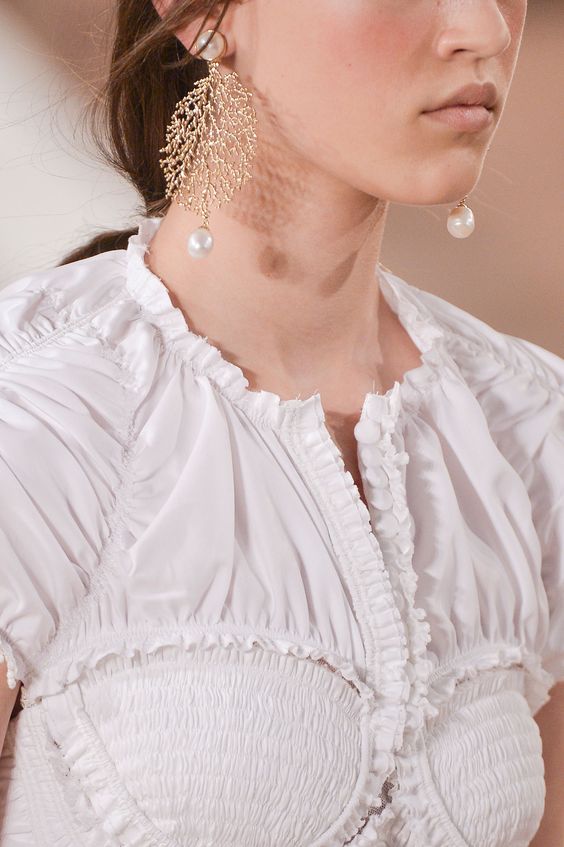 Rose gold statement earrings with pearls, white top